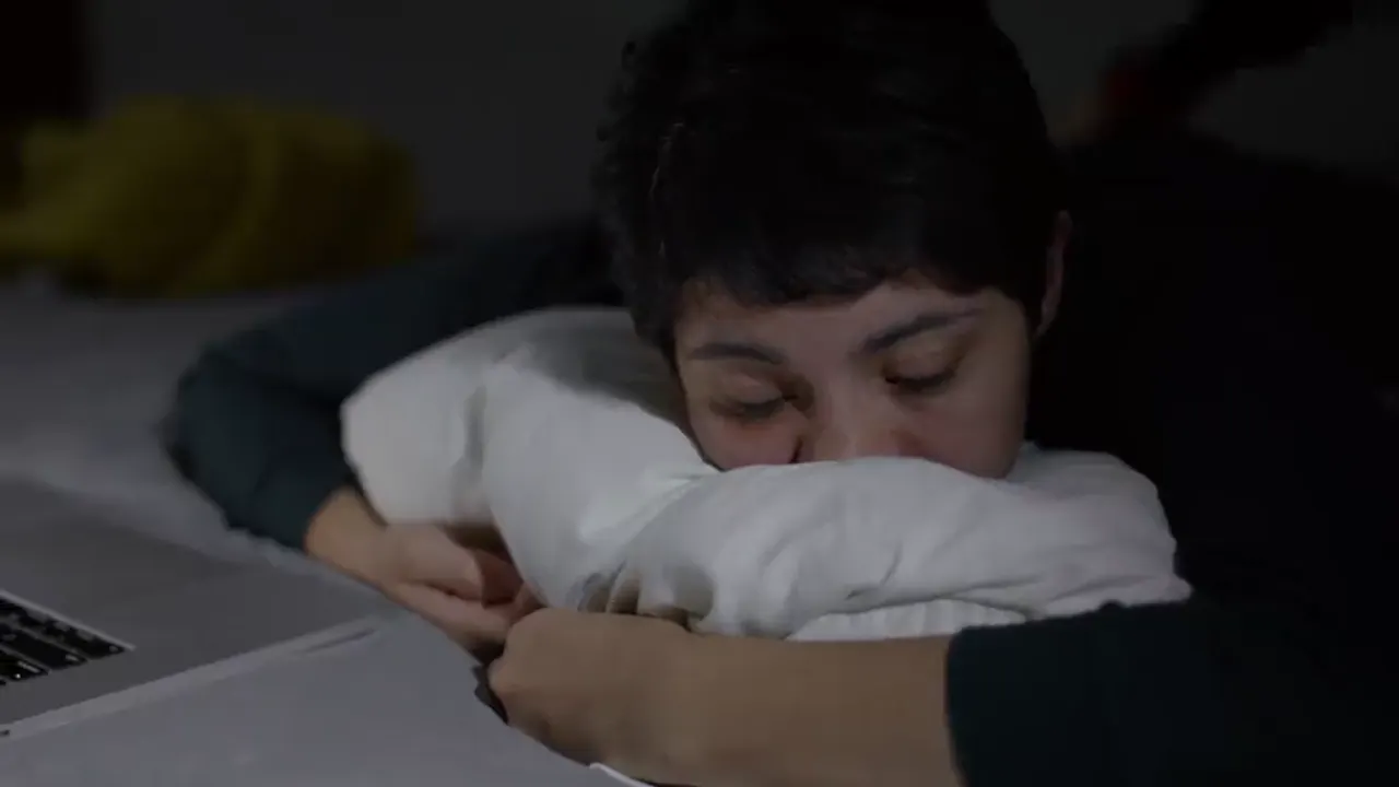 A woman lying awake in bed at night, her face half in the pillow